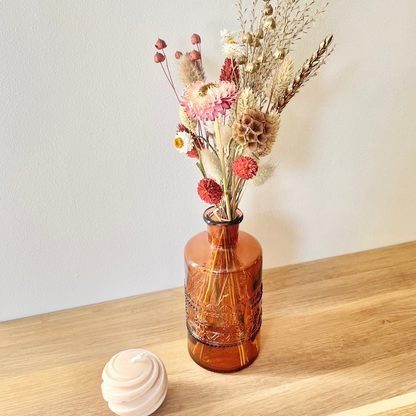 Bouquet de fleurs séchées dans un vase en verre soufflé coloré, rouge